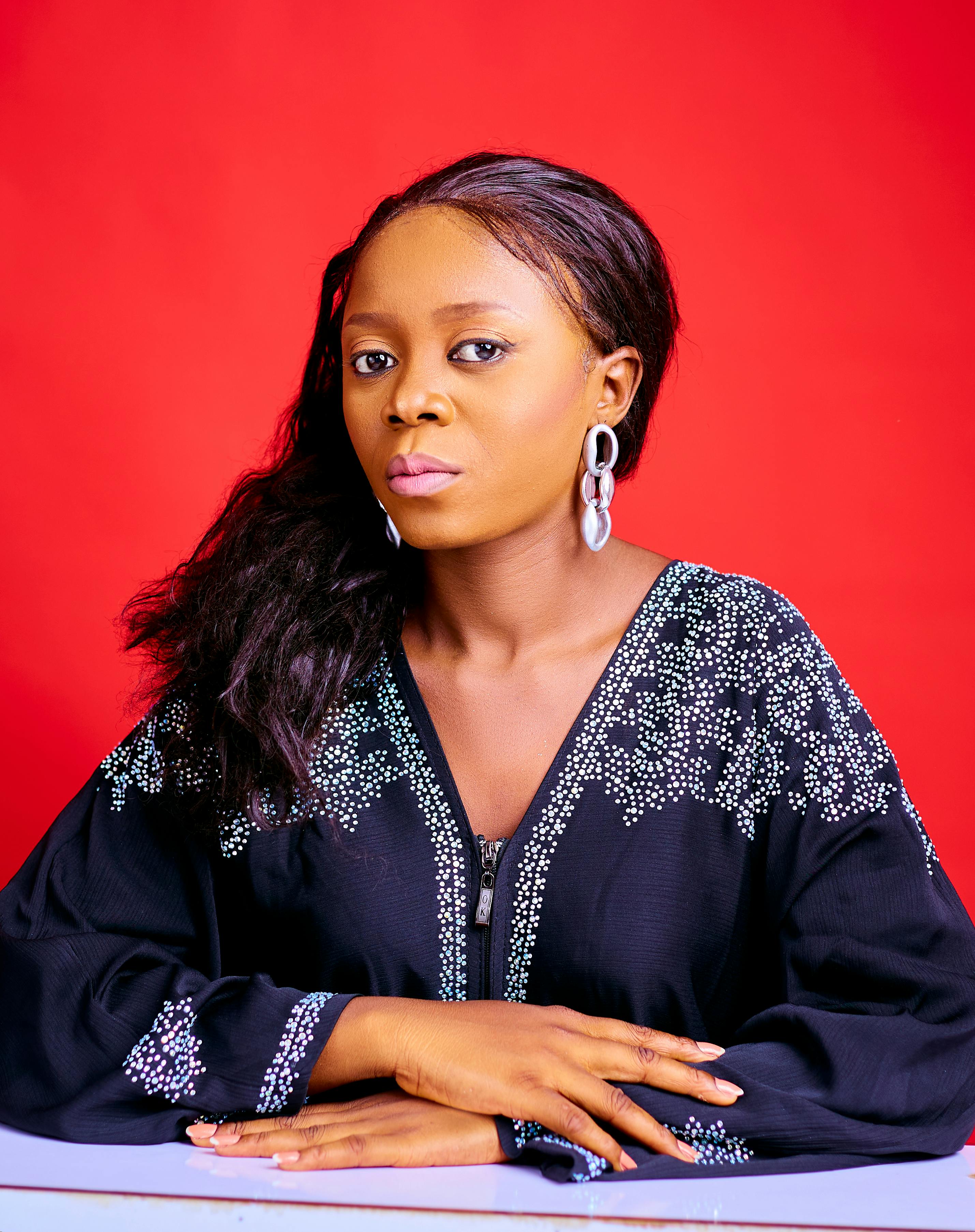 Fashionable woman with bold earrings against a vibrant red background.