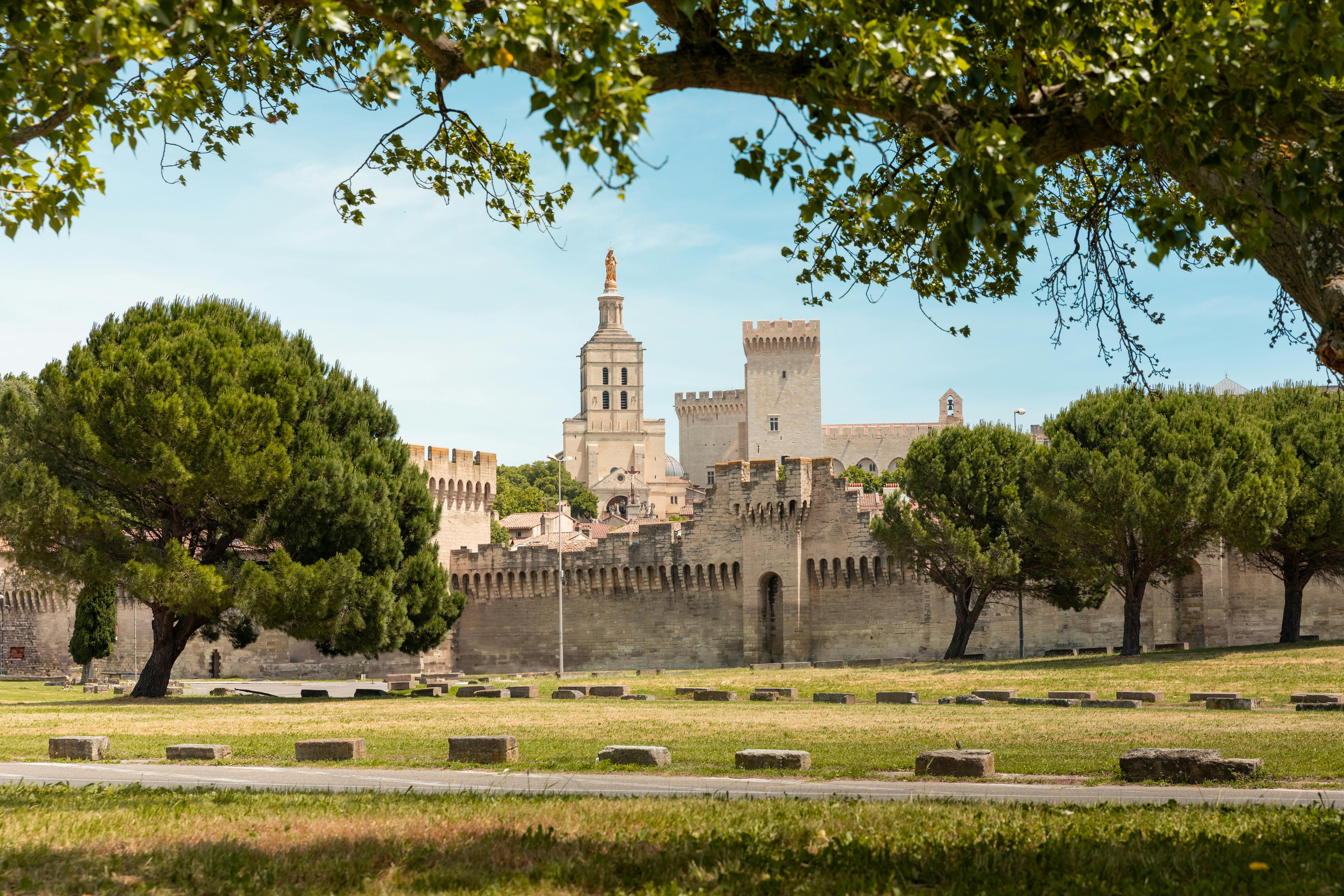 Explore the historic charm of Avignon, France, with its iconic palace and vibrant gardens bathed in natural light.