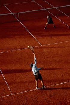 A competitive tennis match in action on a vibrant clay court with players engaged.