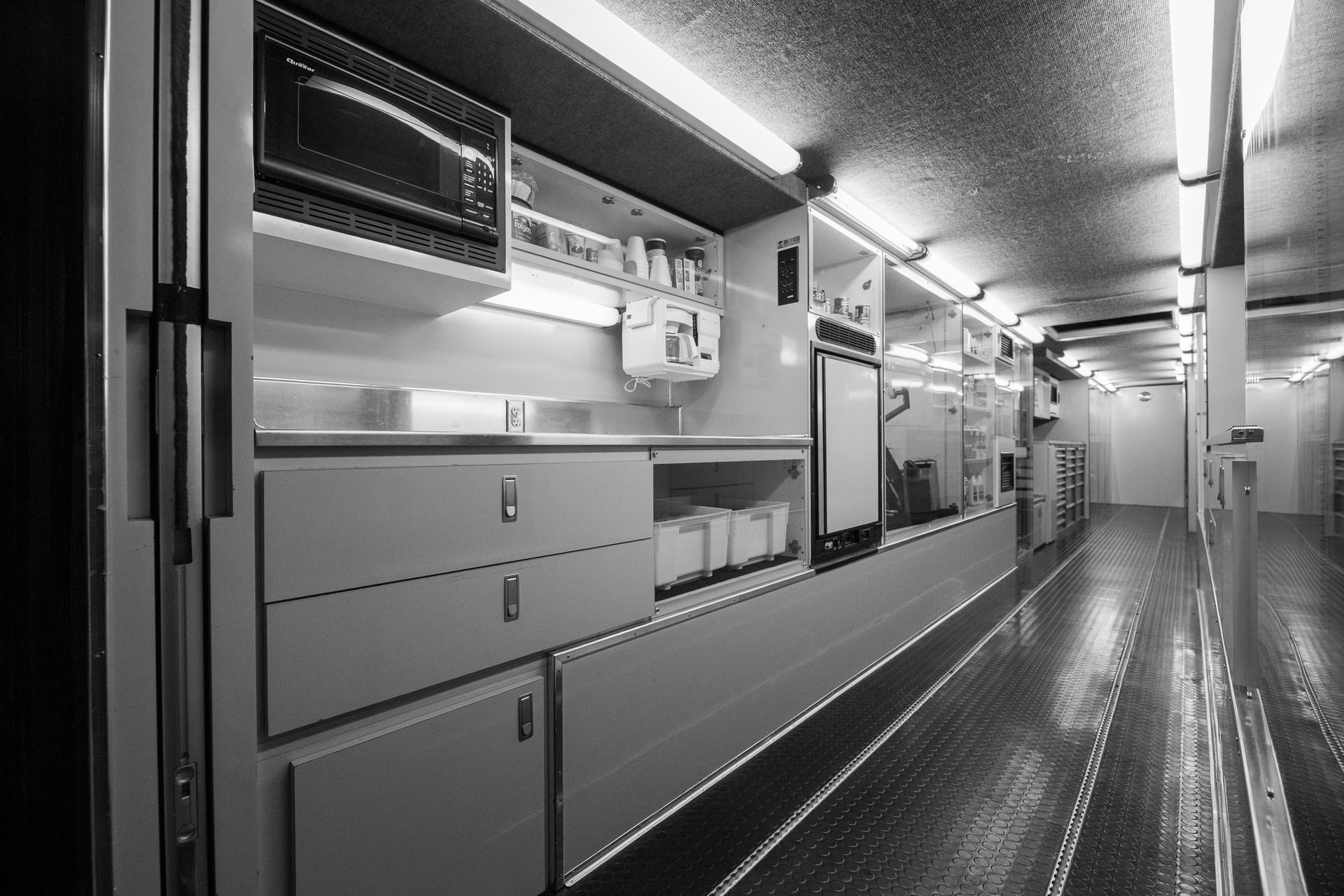 Sleek black and white view of an industrial mobile unit interior, showcasing appliances and storage.