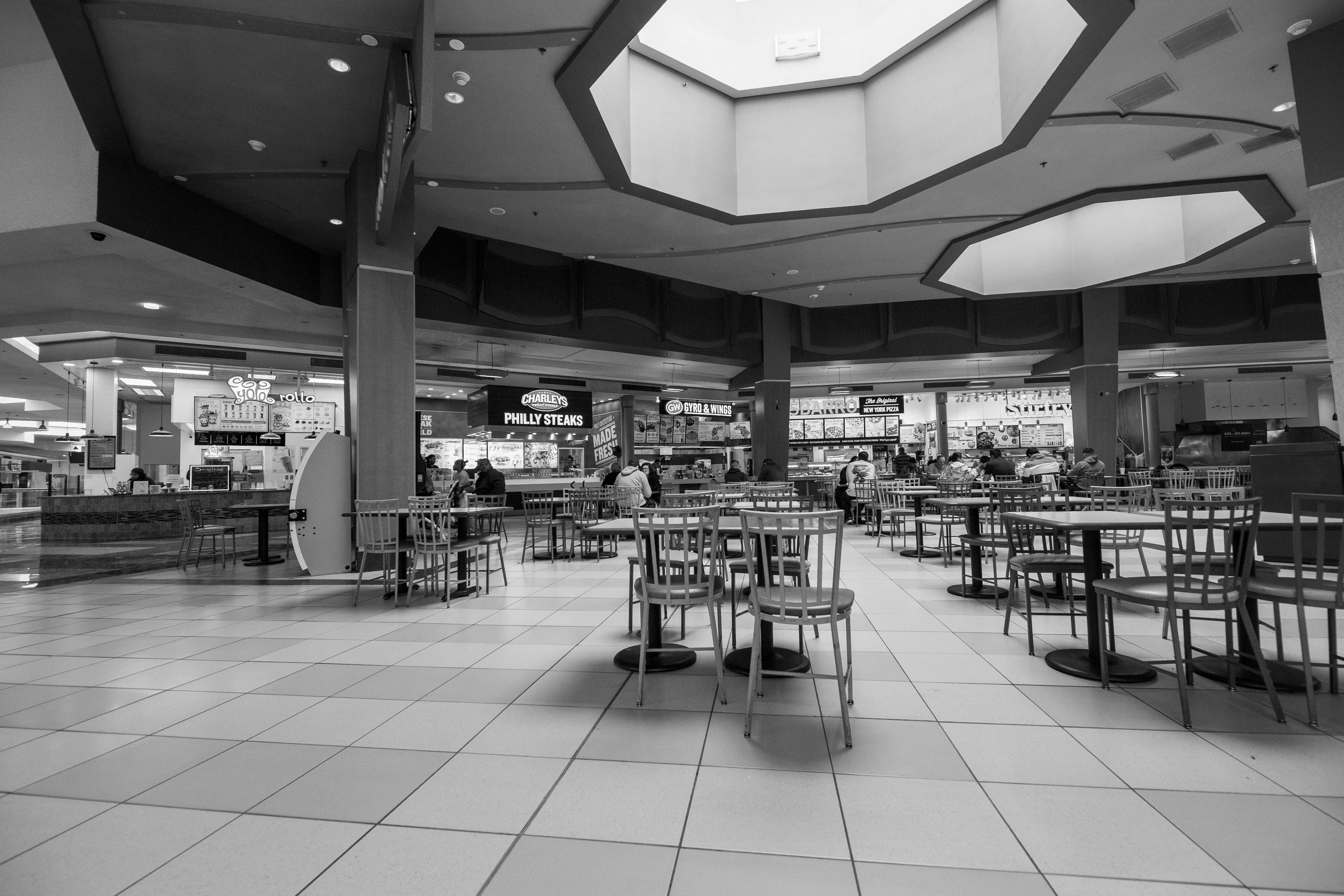 Food court seating with fast food outlets behind — multi-outlet F&B groups need synchronised cockroach treatment across every branch