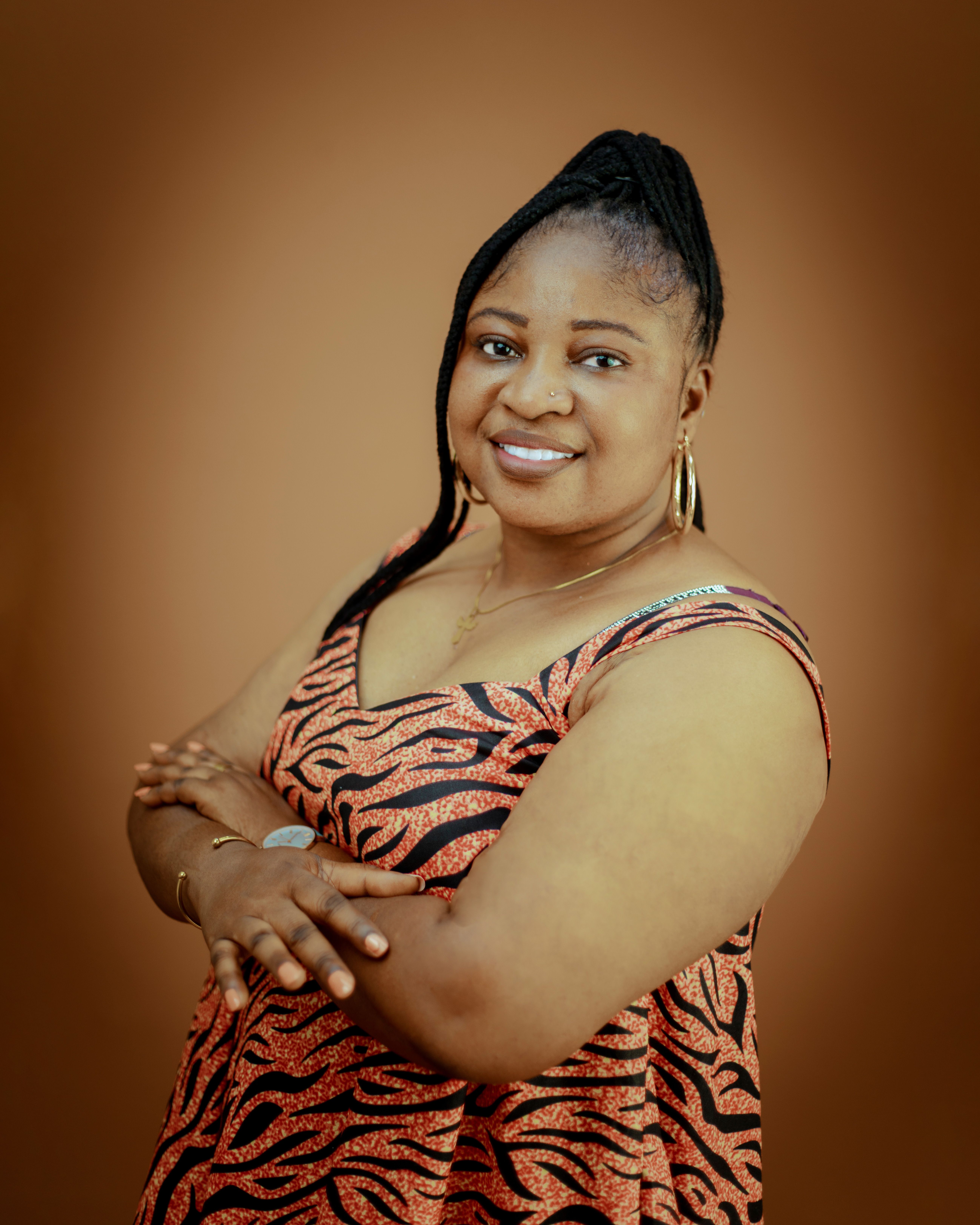 Portrait of a confident woman in an orange zebra print dress against a warm background.