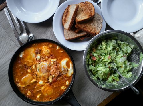 Free Savory shakshuka with toast and salad on a dining table, perfect for brunch. Stock Photo