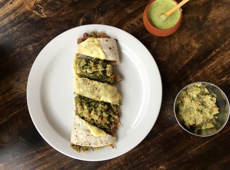Delicious Mexican quesadilla served with guacamole and green sauce on a rustic table.