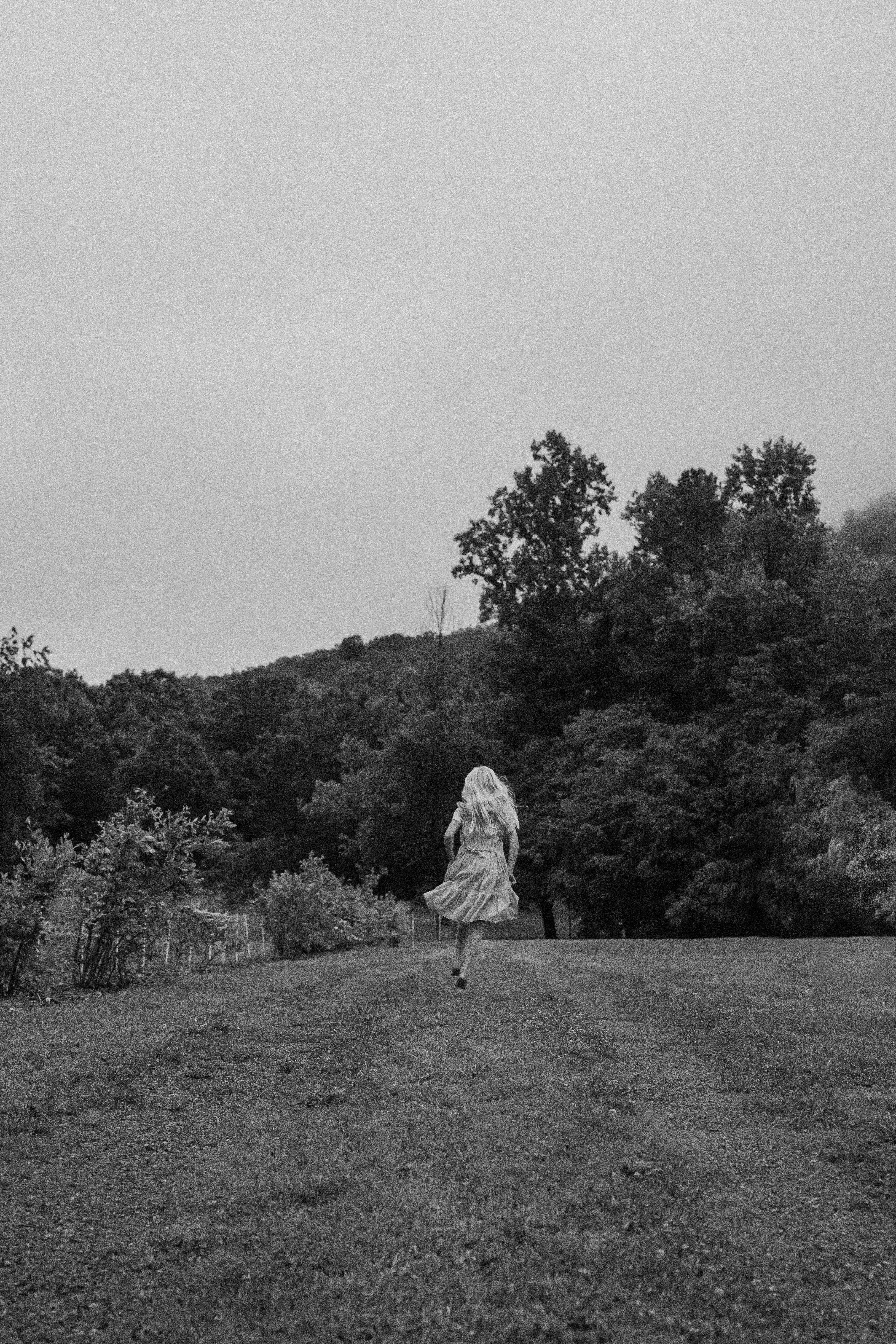 A woman in a dress dashes through a foggy rural landscape, creating a sense of escape and freedom.