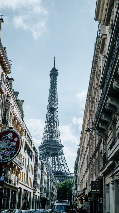 Free Charming view of the Eiffel Tower from a bustling street in Paris, capturing architectural beauty. Stock Photo
