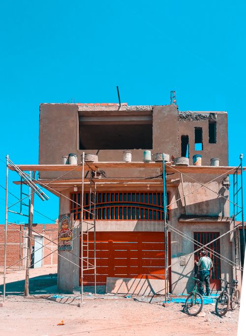 Free Worker at a construction site in Ferreñafe, Peru with scaffolding under a clear blue sky. Stock Photo