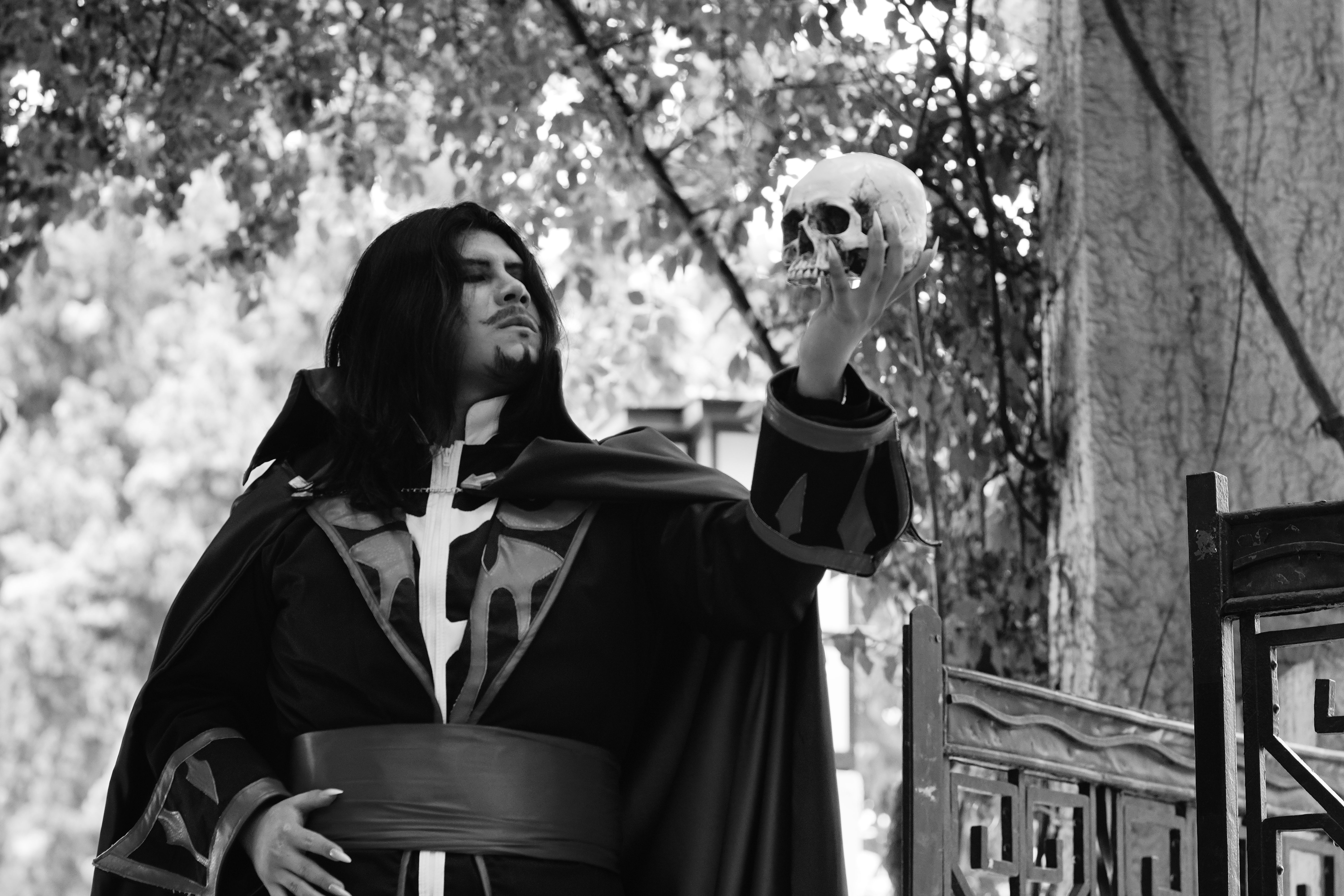 A dramatic scene of a medieval character in costume holding a skull outdoors, evoking introspection.