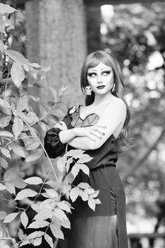 Elegant woman in black dress posing amidst forest foliage, exuding a Gothic charm.
