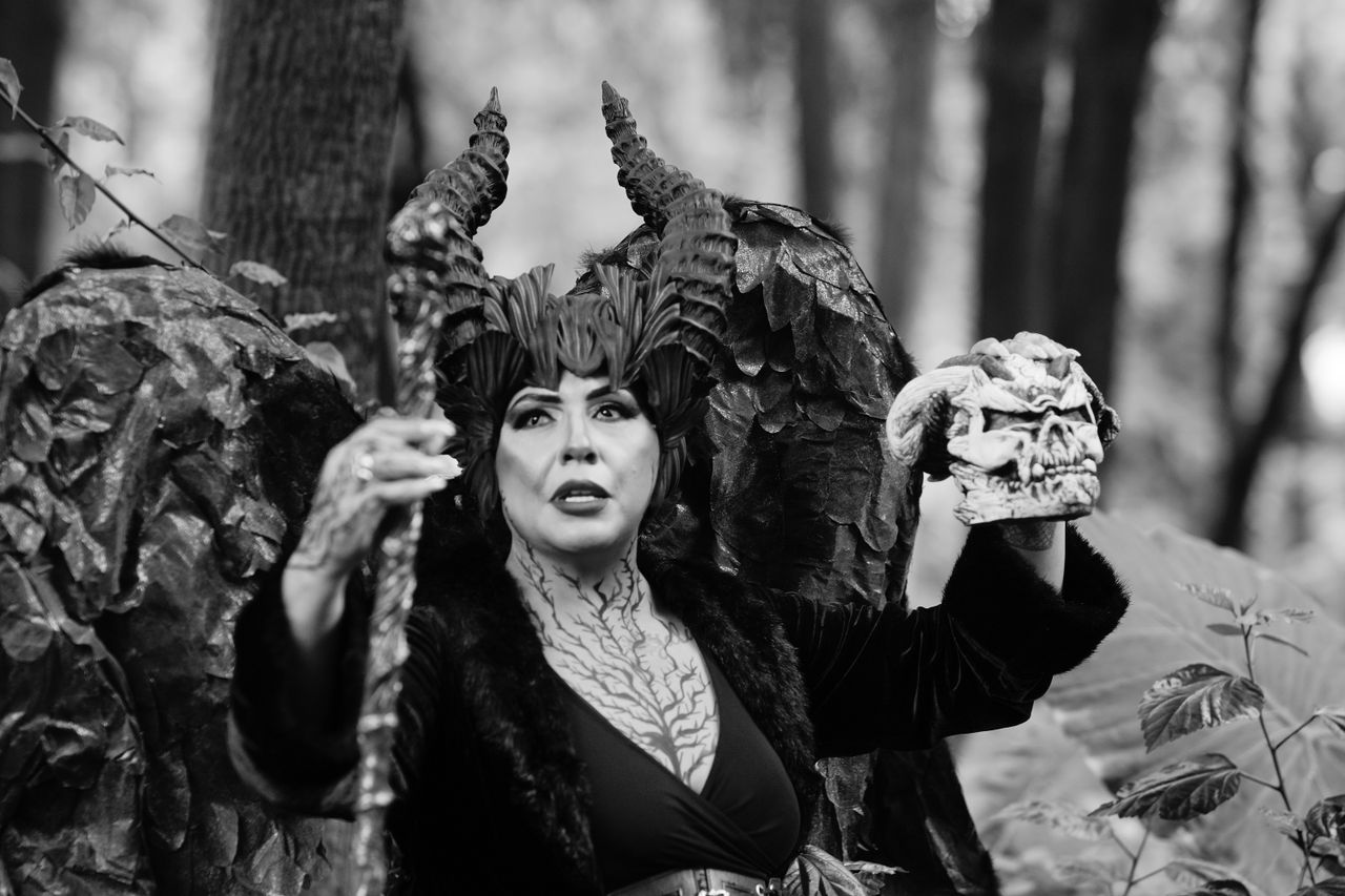 dramatic portrait of a sorceress with horns in a forest holding a skul