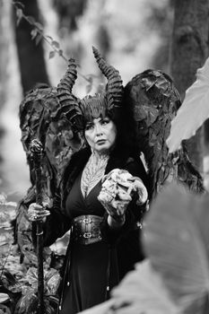 Black and white photo of a majestic dark angel in a forest setting.