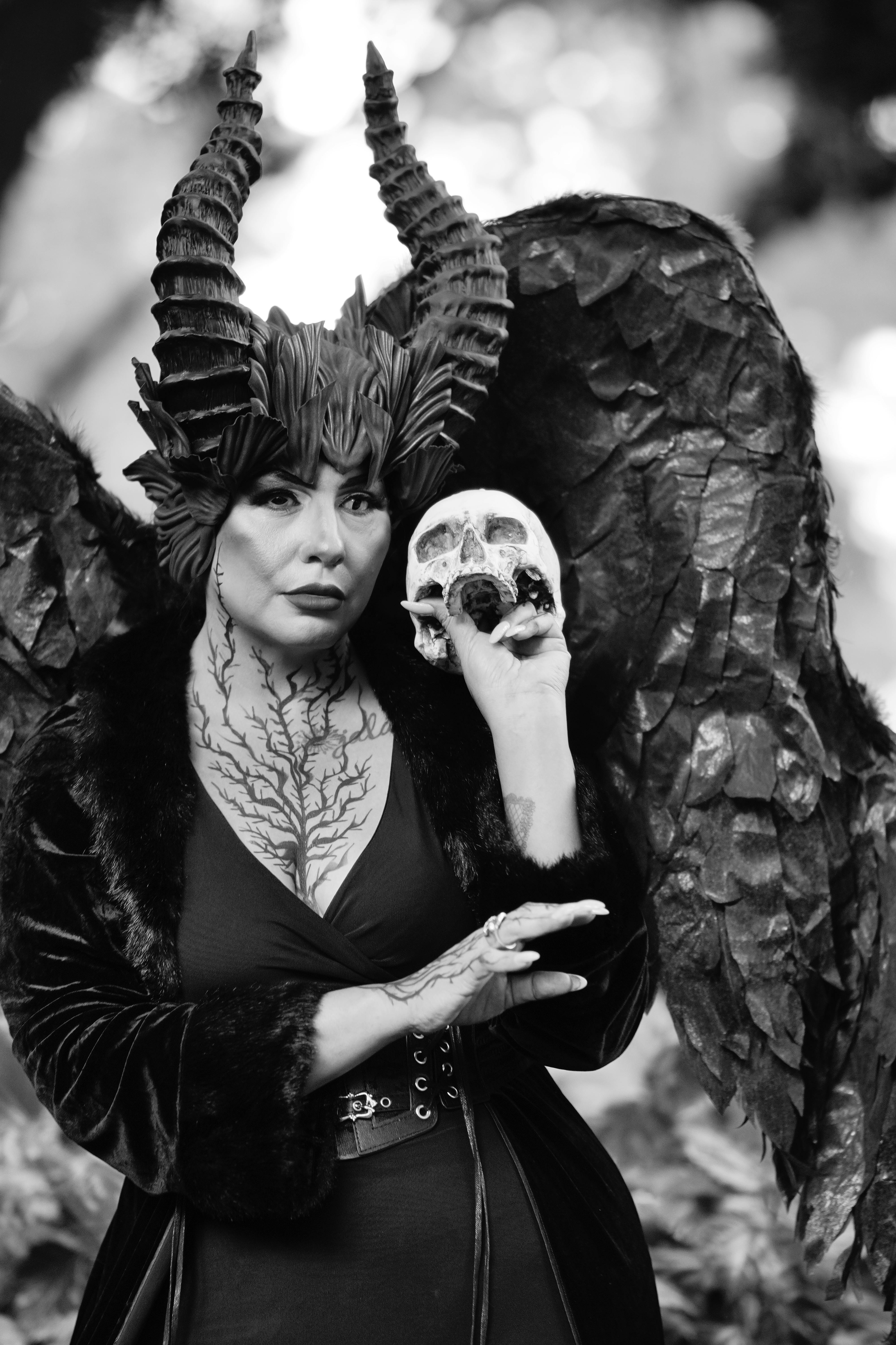 grátis Um personagem místico com chifres e asas segurando uma caveira em um cenário de floresta, exalando uma atmosfera assustadora e dramática. Foto profissional