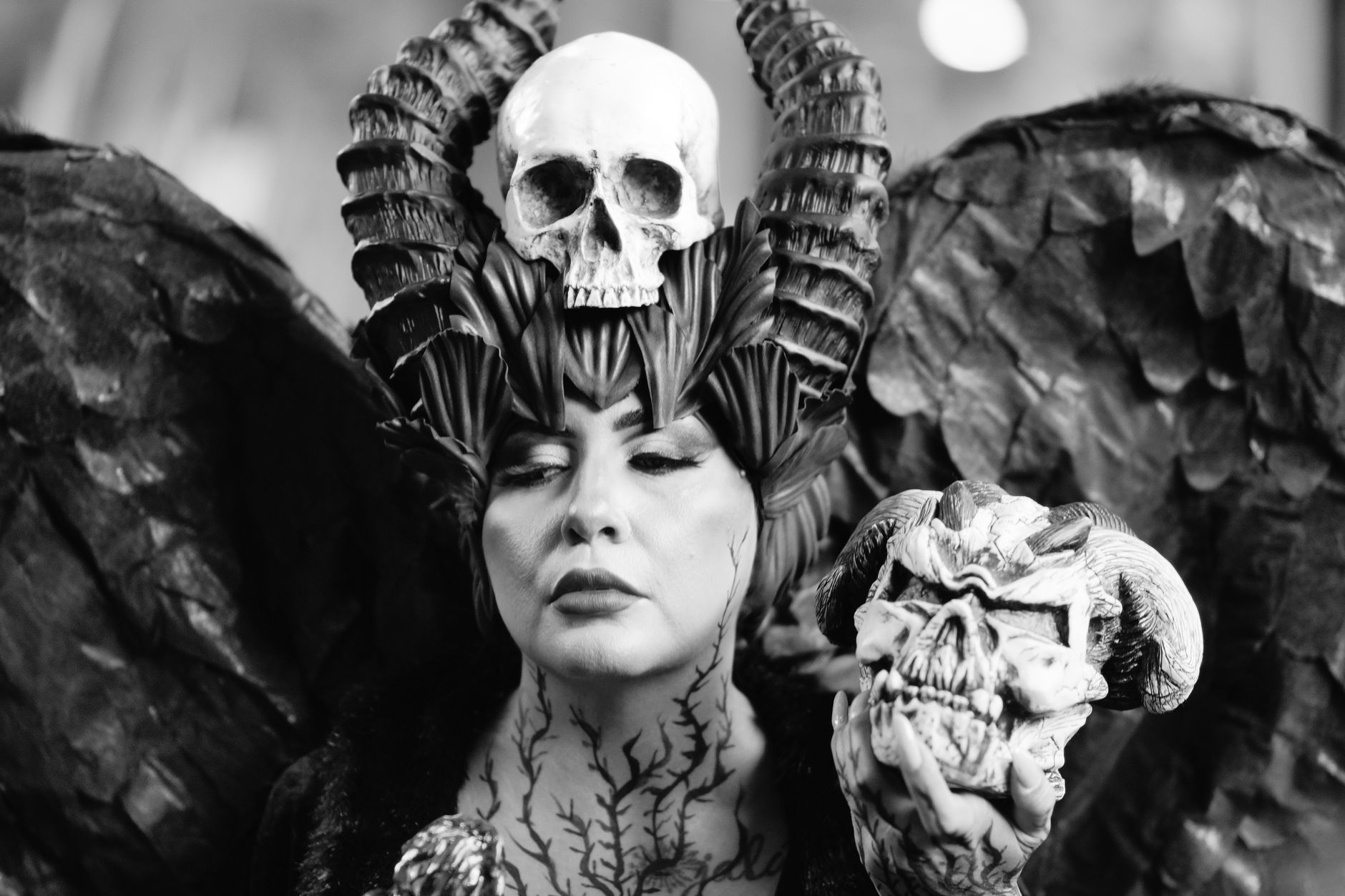 Dramatic black and white portrait of a woman in gothic costume holding a skull.