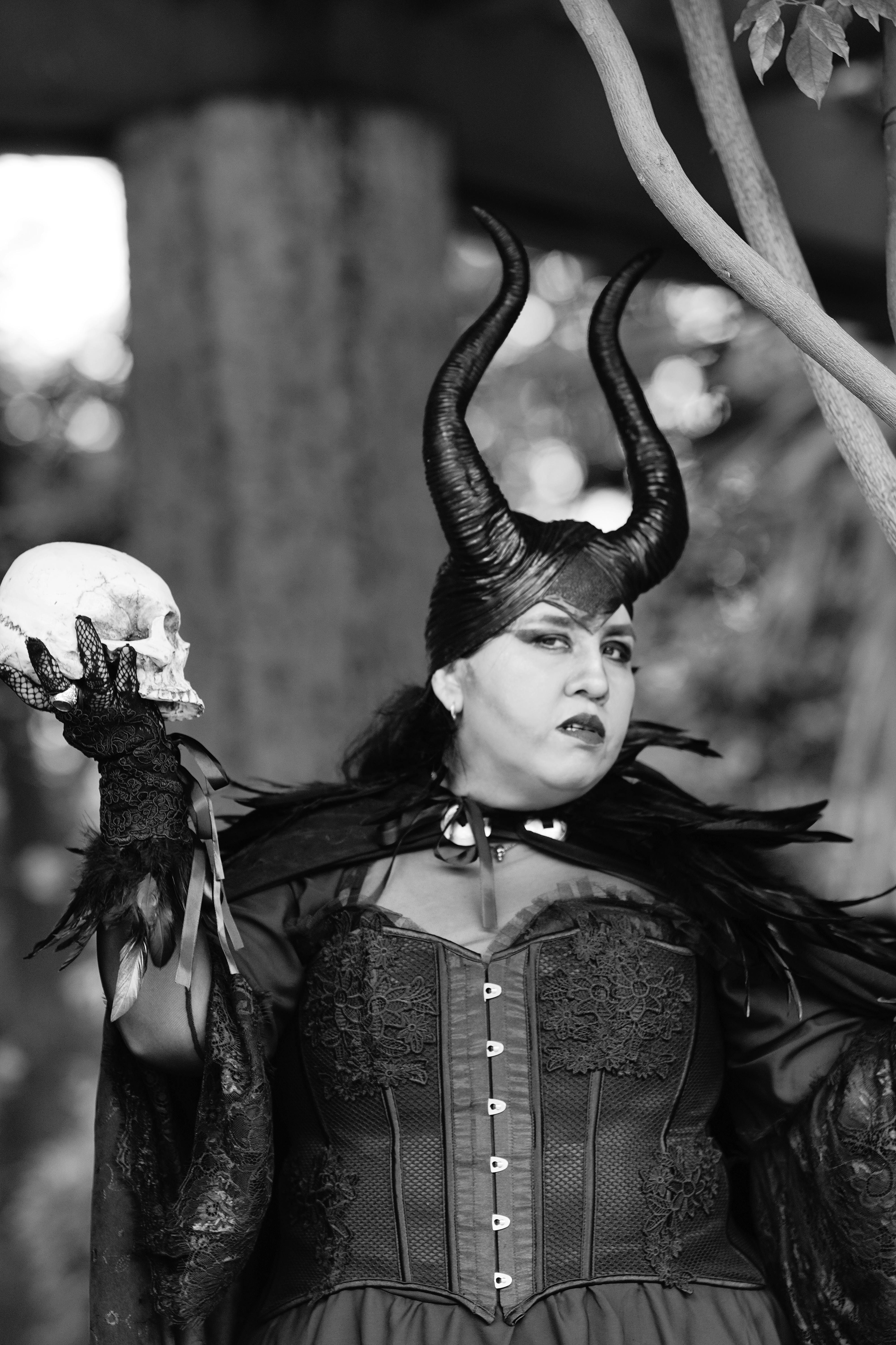 grátis Uma pessoa em uma fantasia gótica segurando uma caveira em um cenário dramático em preto e branco. Foto profissional