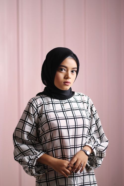 Free Elegant portrait of a woman in a stylish checkered outfit and hijab, captured indoors. Stock Photo