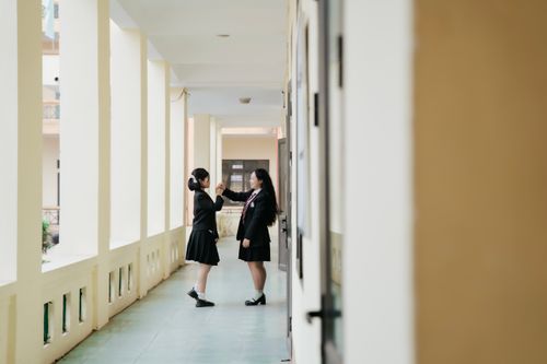 Free Two students in uniforms having a conversation in a school corridor. Bright and friendly atmosphere. Stock Photo