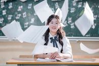 Happy student throws papers in classroom in celebration of school year ending. Cheerful academic success.