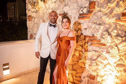 Cuplu formal lângă zid luminat