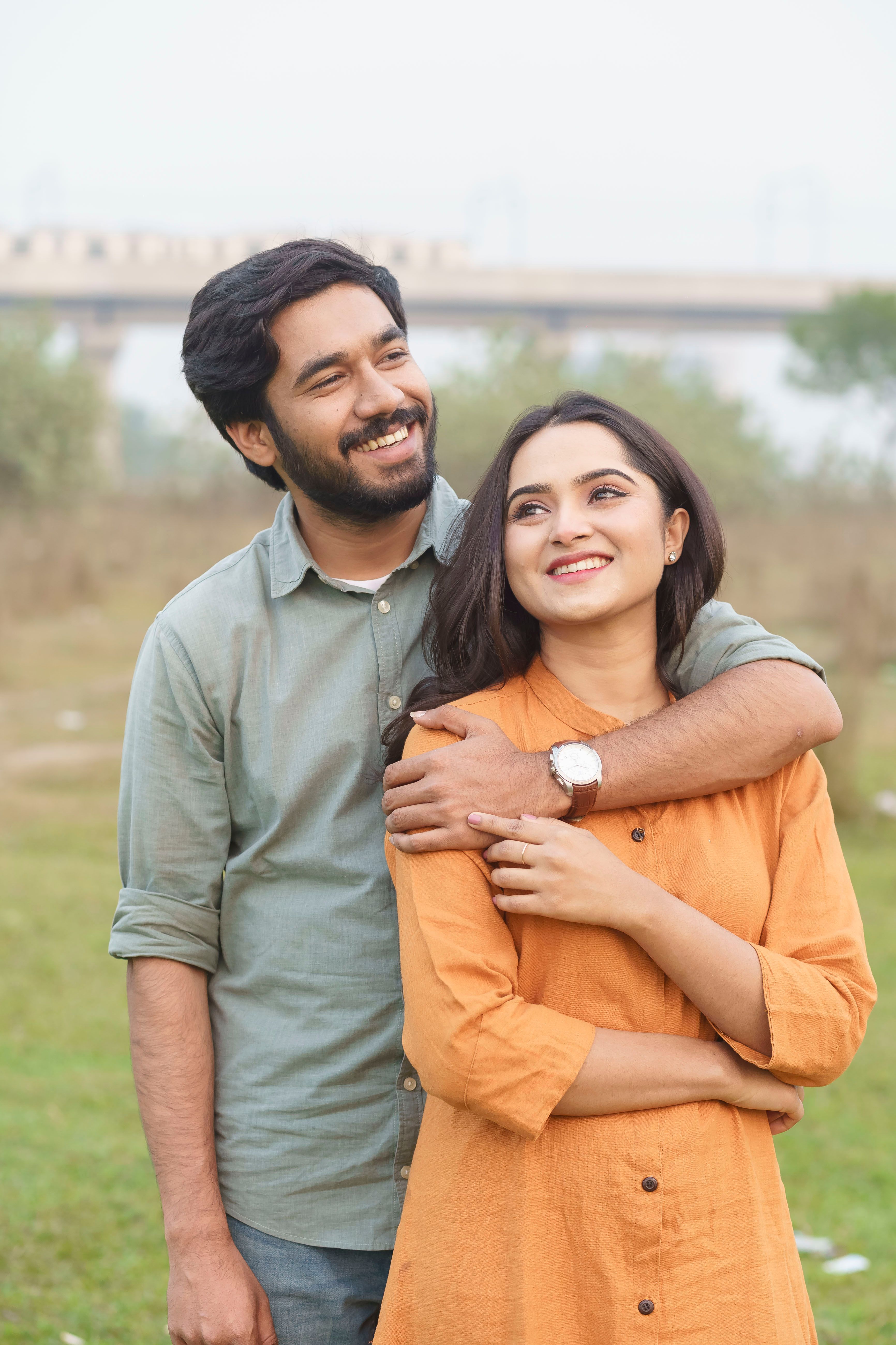 A cheerful couple embracing outdoors with a scenic background, conveying love and warmth.