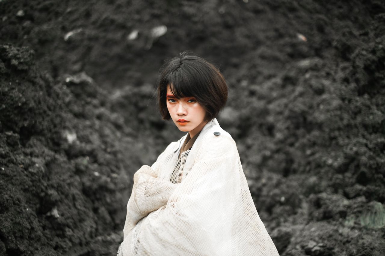 a portrait of a stylish woman outdoors wrapped in a light shawl agains