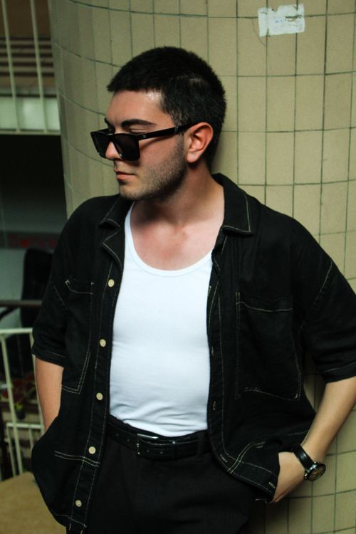Free Stylish young man in sunglasses leaning on a tiled wall indoors. Stock Photo