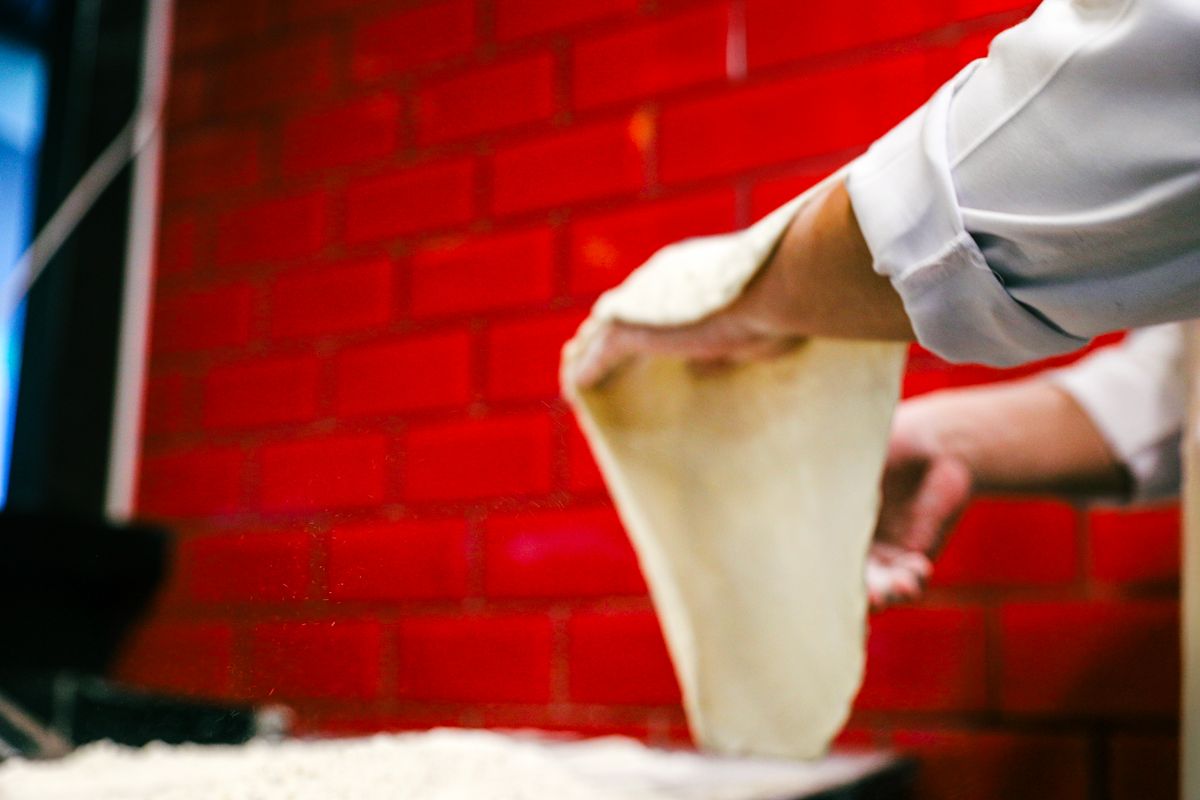 Mani che lavorano l'impasto della pizza