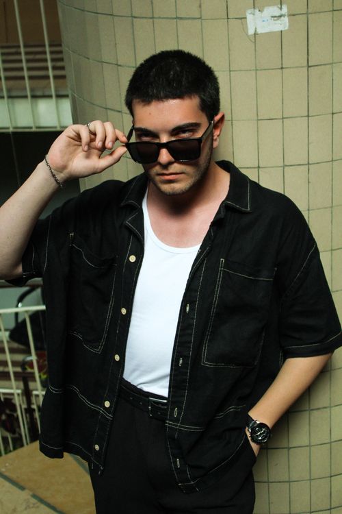 Free Confident man in black outfit and sunglasses posing against a tiled pillar indoors. Stock Photo