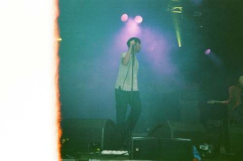 무대에서 노래하는 흰 셔츠와 검은 색 바지를 입은 남자