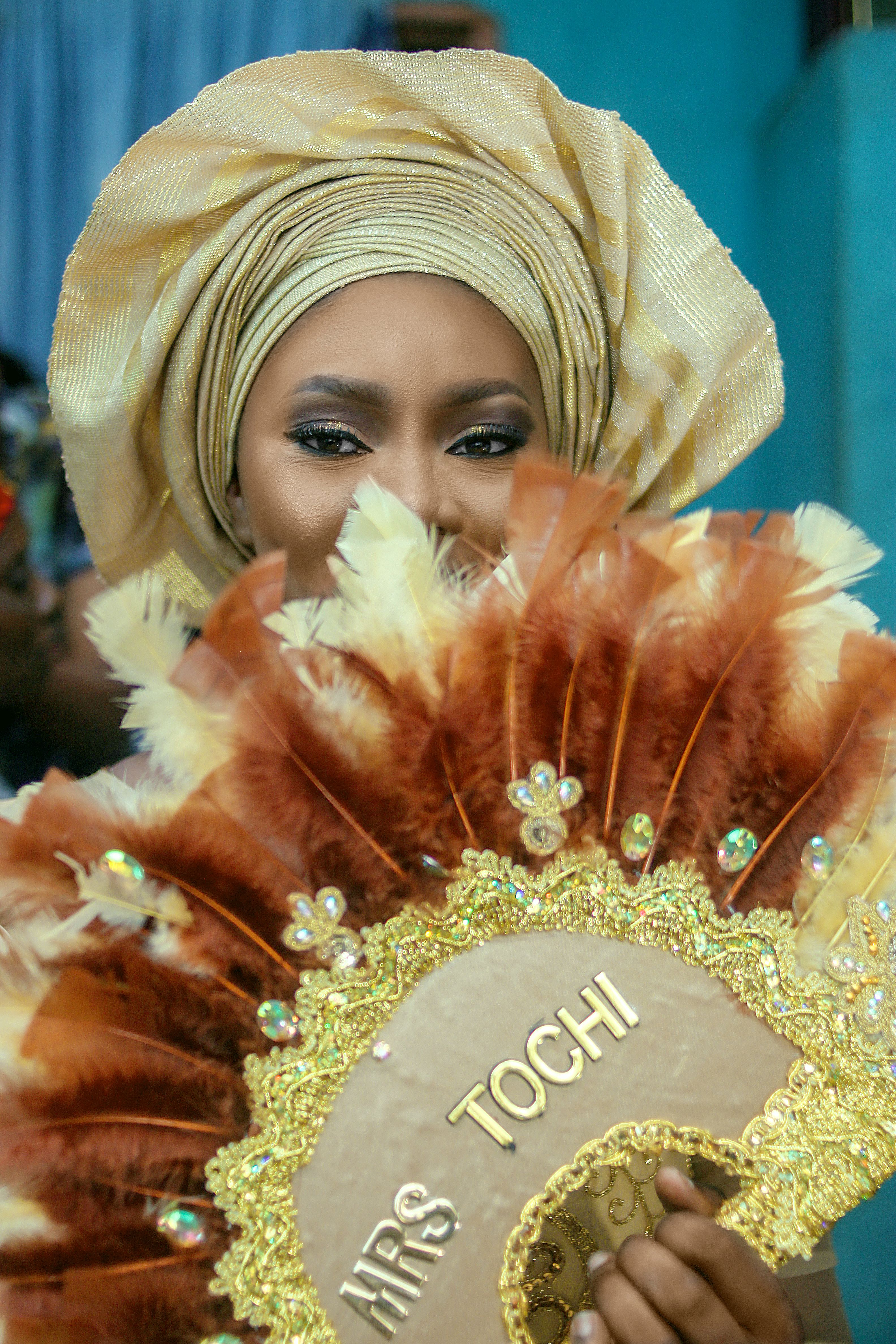 A beautiful Nigerian bride holding a decorative fan, highlighting traditional attire.