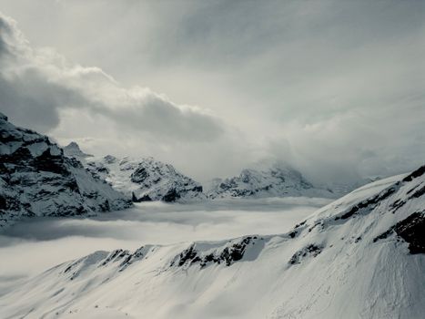Majestic Swiss Alps with snow-covered peaks and clouds in Grindelwald, Switzerland.