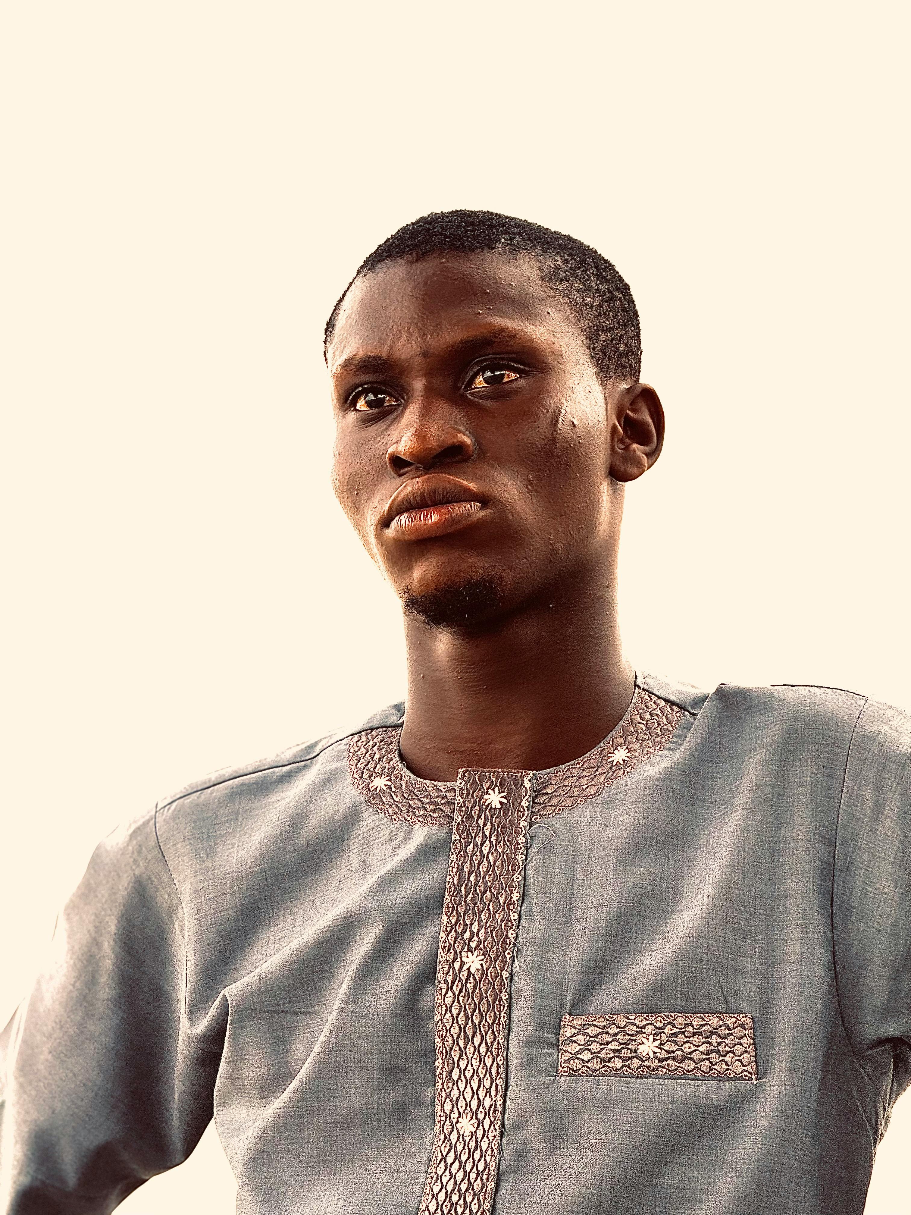 A thoughtful young man gazes upward wearing a cultural traditional outfit.