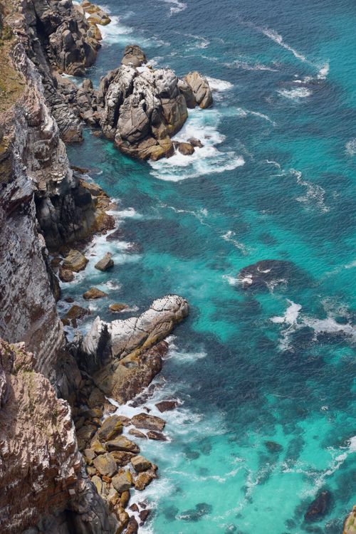 Free A breathtaking aerial view of the rocky Cape Point coastline showcasing stunning turquoise waters and rugged cliffs. Stock Photo