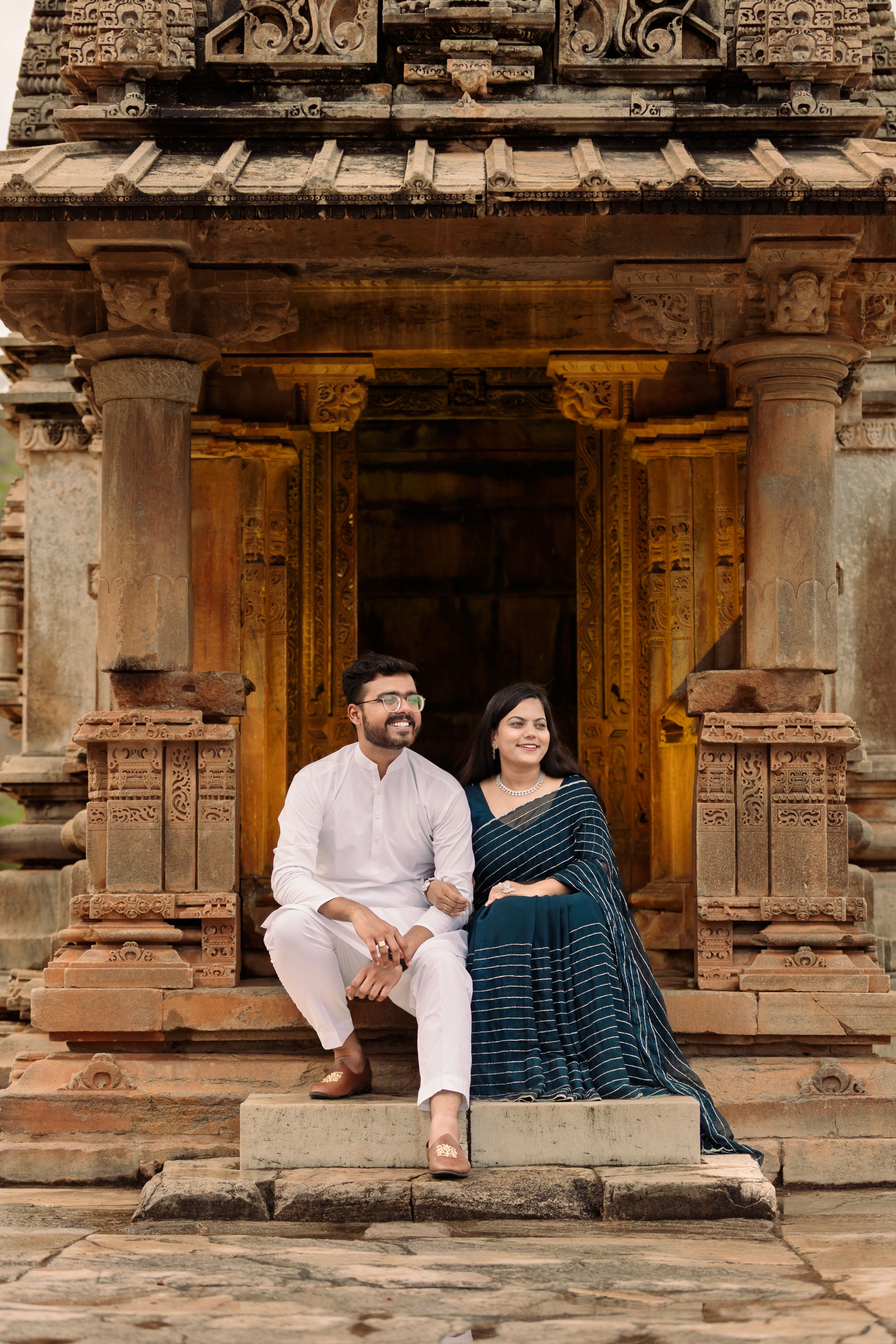 Happy couple sitting on steps of an ancient stone temple, depicting cultural heritage and romance.