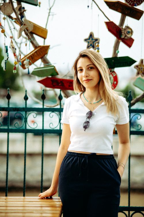 Free Young woman in casual attire standing outdoors with decorative background. Stock Photo