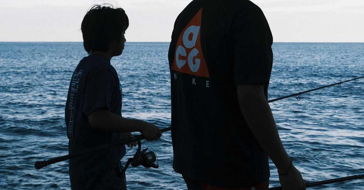 Photo by Daniel Flores A father and son fish together on a rocky Hawaiian shoreline at sunset, with a serene ocean view.