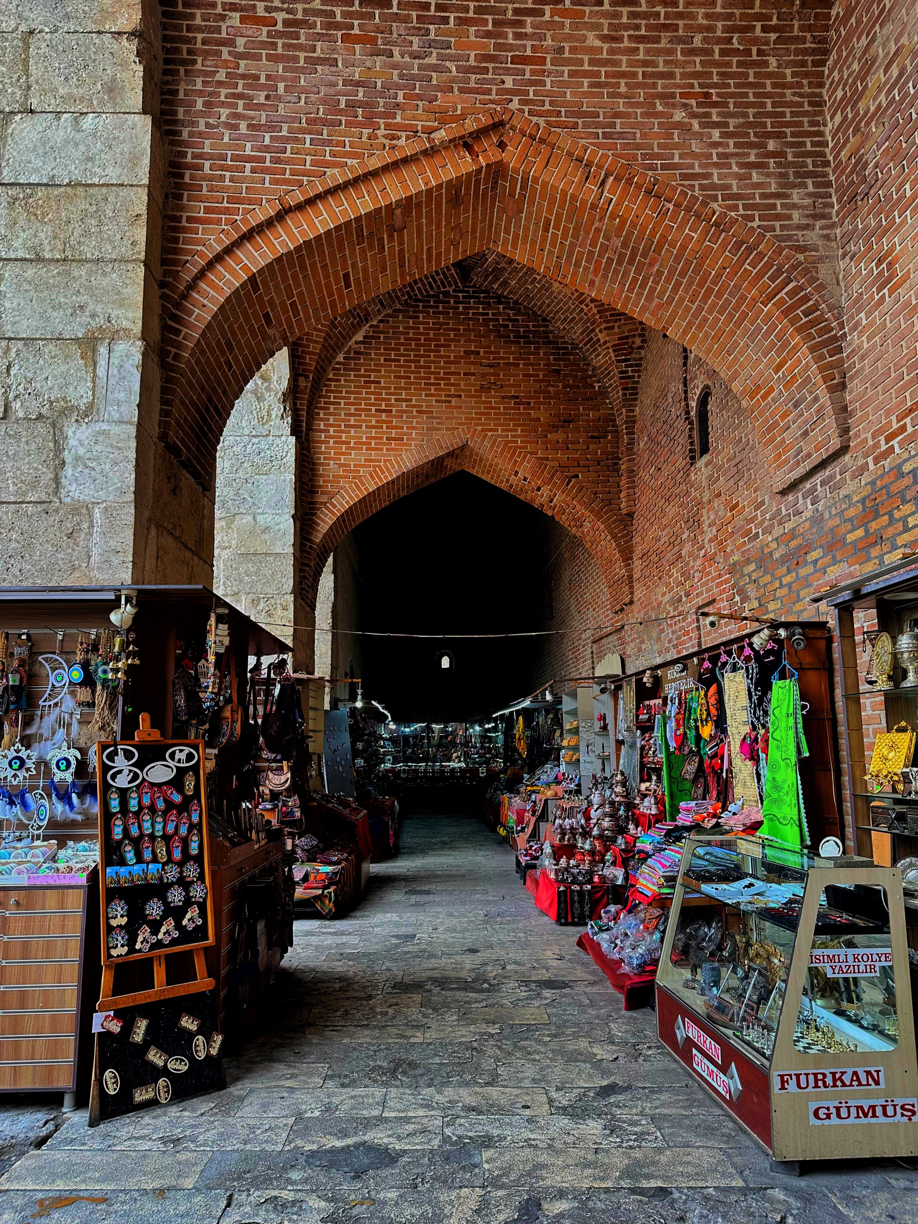 A captivating scene of a historic bazaar alley with colorful goods and brick archways.