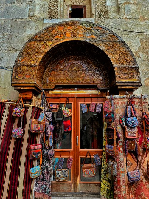 Free Ornate wooden arch entrance showcasing vibrant handmade bags and rugs in a traditional bazaar. Stock Photo