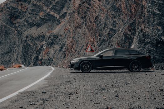 A sleek luxury car parked against a stunning mountainous backdrop.
