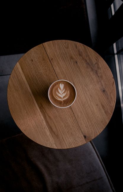 Top-down shot of a cappuccino with latte art on a wooden table, perfect for coffee lovers.