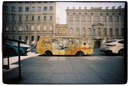 Free Yellow van with graffiti parked between buildings on a city street, showcasing urban art culture. Stock Photo