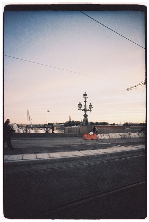 Free Man on bridge at sunset with lamp posts and distant cityscape. Stock Photo