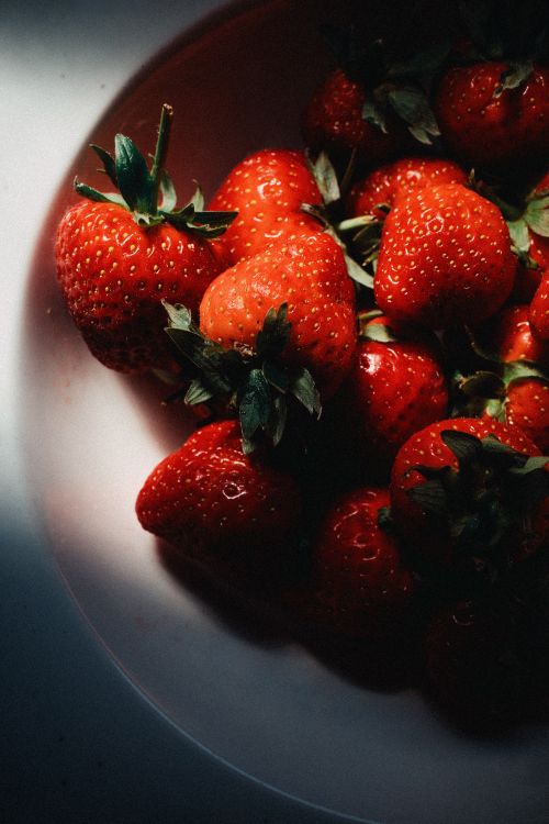 Free A close-up of fresh strawberries with dramatic natural lighting, highlighting texture and color. Stock Photo