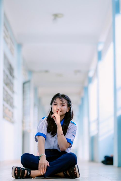 Free Young student sitting cross-legged in a bright school hallway. Stock Photo