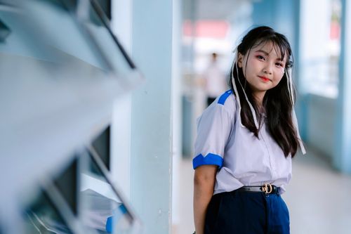 Free Confident young student in uniform smiling in a school hallway, embodying education and youth. Stock Photo