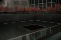 秋天的树木和城市背景映衬着9/11纪念池的阴沉景色