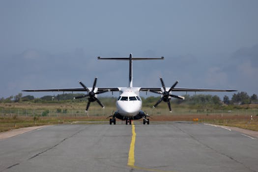 Front view of a propeller airplane on a runway, ready for takeoff under a clear sky.