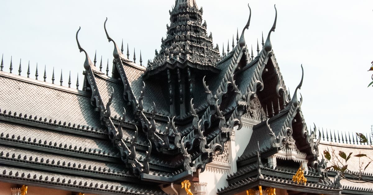 Ornate Thai temple architecture with a decorative gold roof under bright sunlight