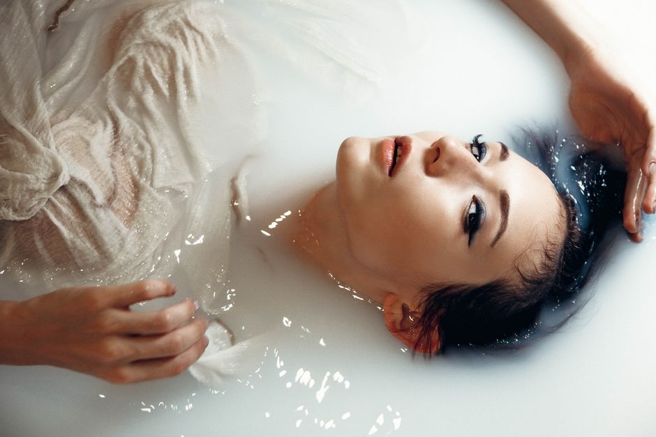 A serene portrait of a woman in a luxurious milk bath with soft lighting.