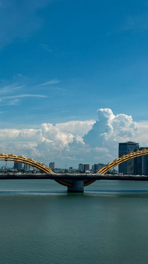 Free Beautiful blue skies over Dragon Bridge in Da Nang, Vietnam, with a city skyline backdrop. Stock Photo