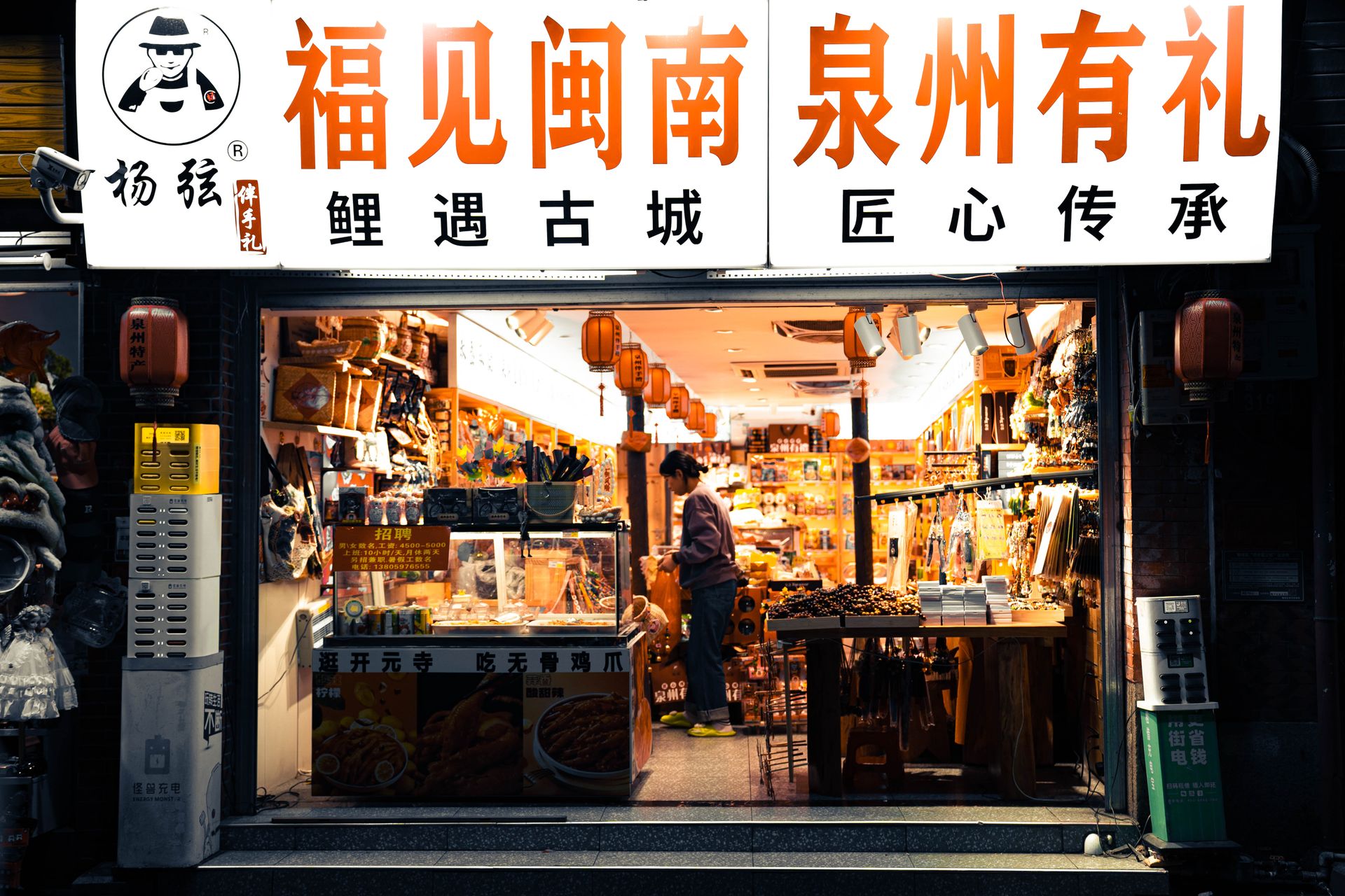 A bustling shopfront in a street market in Quanzhou, vividly lit and filled with local goods and lanterns.